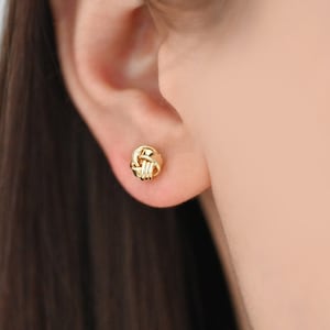 May include: Gold knot stud earrings. The earrings are small and delicate, and they are perfect for everyday wear.