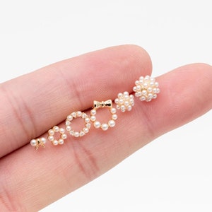 May include: Five pairs of pearl earrings in different styles, including a circle, a bow, and a cluster. The earrings are all gold-toned and feature small, white pearls.