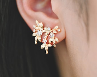 May include: Gold leaf earrings with a delicate floral design and clear cubic zirconia stones.