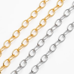 Könnte beinhalten: Zwei Ketten, eine goldene und eine silberne, liegen nebeneinander auf einem weißen Hintergrund. Beide Ketten bestehen aus ovalen Gliedern.
