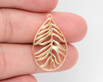 May include: Gold leaf pendant charm with a delicate, intricate design. The charm is shaped like a teardrop and features a detailed leaf pattern.