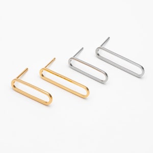 May include: Three pairs of oval-shaped earrings in gold, silver, and rose gold. The earrings are simple and minimalist, with a sleek, modern design.
