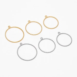 Pode incluir: Seis argolas de salto douradas e prateadas com acabamento texturizado. As argolas são de tamanhos diferentes e têm um pequeno laço na parte superior.