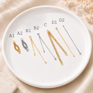 Peut inclure: Une collection de connecteurs de bijoux en métal étiquetés A1, A2, B1, B2, C, D1 et D2. Les articles comprennent des maillons de chaîne dorés et argentés, certains avec de petites boucles circulaires et d'autres avec des textures perlées.