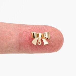 May include: Gold-toned metal bow charm with a loop for attaching to jewelry or other crafts.