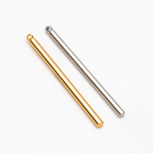 May include: Two metal rods, one gold and one silver, with rounded ends.