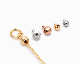 May include: A collection of jewelry findings in various metallic finishes. The assortment includes gold, silver, rose gold, and gold-toned metal components, such as clasps and beads, for jewelry making. The findings are displayed against a white background.