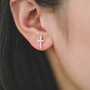 May include: A pair of small gold cross earrings with clear cubic zirconia stones.