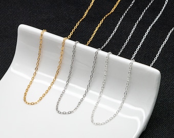 May include: Three silver and gold chains on a white surface. The chains are all the same style, but different lengths.