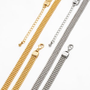 May include: Two gold and silver chain necklaces with a box clasp closure. The chains are made of multiple rows of small, round beads.