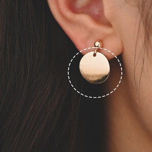 May include: Gold circle earrings with a smooth, shiny finish. The earrings are a simple and elegant design.