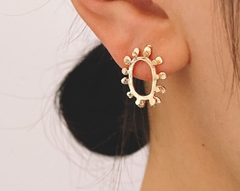 May include: Gold oval hoop earrings with a textured, beaded design.