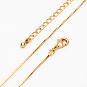 May include: A gold chain necklace with a lobster clasp fastening. The chain is made of small, round links.