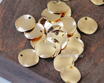 May include: A pile of gold-colored metal circles with a small hole in each one. The circles are slightly irregular in shape and have a shiny finish.