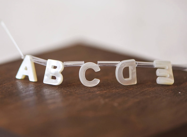 May include: White plastic letters spelling out the word "ABCDE" on a brown wooden surface.