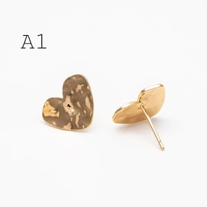 May include: A pair of heart-shaped stud earrings. One earring has a textured, mottled surface in shades of gold and brown. The other earring is a solid gold color. The text "A1" is in the upper left corner.