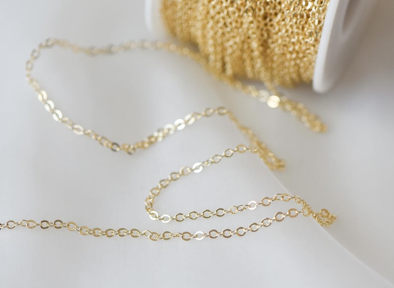 May include: A close-up of a gold chain, a popular jewelry making supply. The chain is delicate and has a fine, oval-shaped link.
