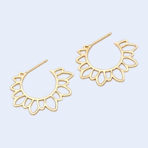 Puede incluir: Un par de pendientes de aro dorados con un delicado dise&ntilde;o floral. Los pendientes est&aacute;n hechos de metal y tienen un estilo simple y elegante.
