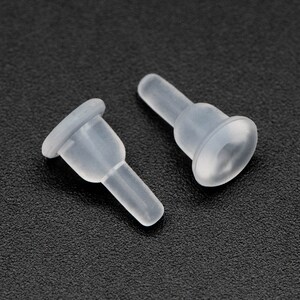 May include: Two clear plastic caps with a small, round, flat base and a thin, cylindrical stem. The caps are designed to fit over the ends of a cylindrical object.