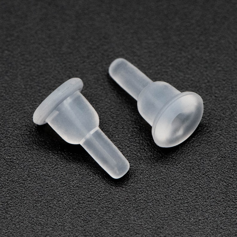 May include: Two clear plastic caps with a small, round, flat base and a thin, cylindrical stem. The caps are designed to fit over the ends of a cylindrical object.