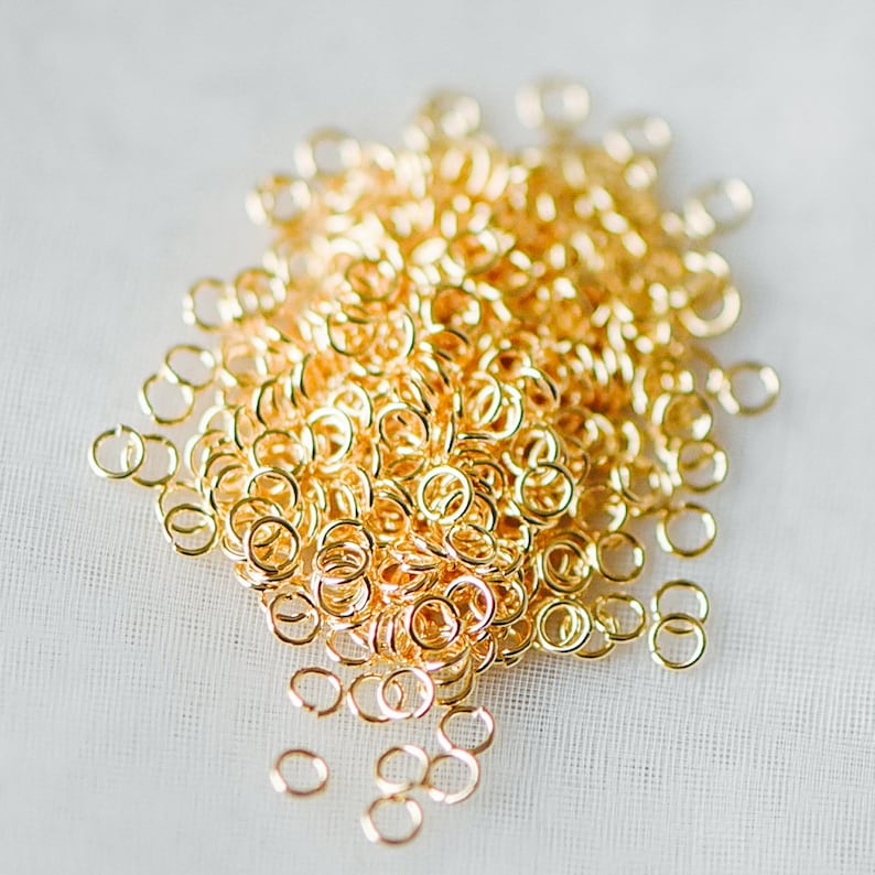 May include: A large pile of gold jump rings. The rings are small and round, and they are all linked together.