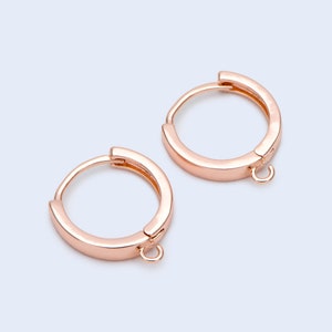 May include: A pair of rose gold hoop earrings with a small jump ring attached to each hoop.