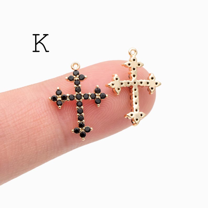 Pu&ograve; includere: Due ciondoli a forma di croce color oro. Una croce &egrave; adornata con pietre preziose nere, mentre l'altra &egrave; semplice. La lettera "K" &egrave; nell'angolo in alto a sinistra. Questi ciondoli sono adatti per la creazione di gioielli o lavori artigianali a tema religioso.