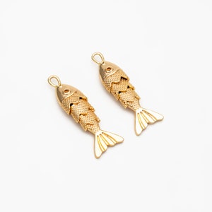 Peut inclure: Deux breloques de poisson dorées avec une surface texturée. Les poissons sont empilés l'un sur l'autre et ont une boucle en haut pour être attachés à un collier ou un bracelet.