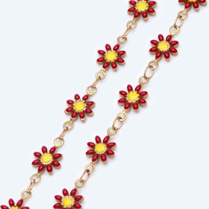 Puede incluir: Un collar de cadena dorada con abalorios de flores de esmalte rojo y amarillo. Las flores tienen un centro amarillo y pétalos rojos.