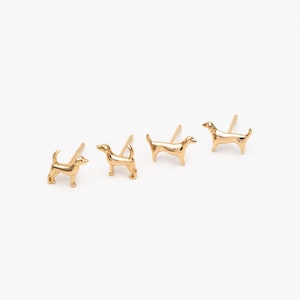 May include: Three gold dog-shaped stud earrings. The earrings are different sizes, with the smallest on the left and the largest on the right.