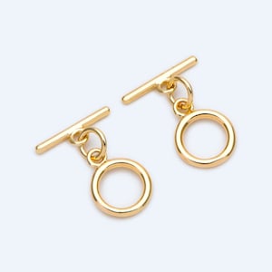 May include: Two gold-toned metal toggle clasps with a round ring attached to each. The clasps are designed for jewelry making or other craft projects.