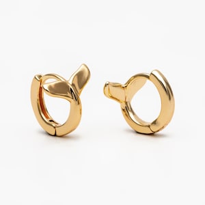 May include: A pair of gold hoop earrings with a unique twist design. The earrings are simple and elegant, making them a versatile accessory for any occasion.