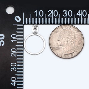 May include: A silver ring with a small row of diamonds on the band. The ring is shown next to a US quarter for size comparison.