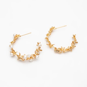 May include: A pair of gold hoop earrings featuring a delicate floral design and small white pearls. The earrings are lightweight and ideal for everyday wear.