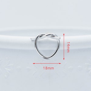 May include: Silver heart-shaped ring with a twisted knot design. The ring measures 18 mm wide and 14 mm high.