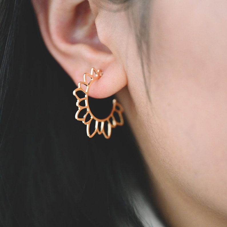Puede incluir: Pendientes de aro dorados con un delicado dise&ntilde;o floral. Los pendientes se llevan en la oreja.