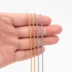 Peut inclure: Gros plan sur trois colliers d&eacute;licats. Deux sont dor&eacute;s et un est argent&eacute;. Les cha&icirc;nes ont un aspect textur&eacute; et scintillant. Les colliers sont pr&eacute;sent&eacute;s sur un fond blanc.