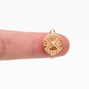 Puede incluir: Conector de metal dorado con un diseño circular adornado. El conector tiene dos bucles a cada lado para sujetar joyas.