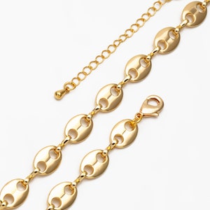 May include: Gold-colored necklace featuring a series of oval-shaped links, connected by smaller, delicate bars. The necklace has an adjustable chain and a lobster clasp closure. The jewelry is displayed against a white background.