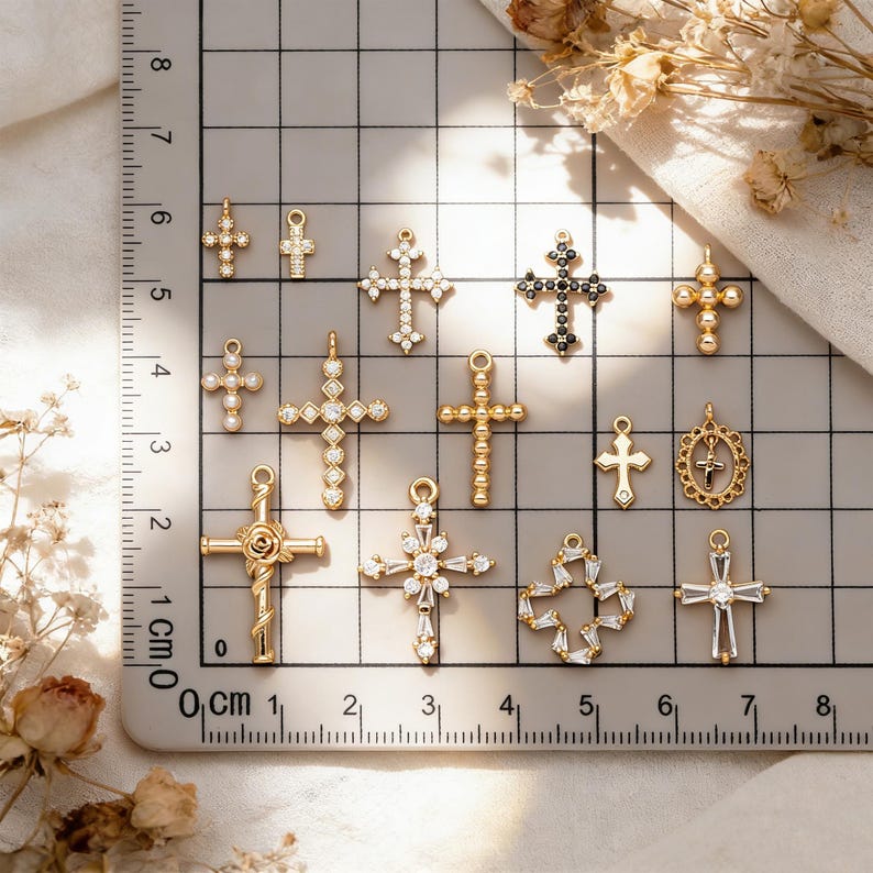 Pu&ograve; includere: Una collezione di pendenti a croce dorati e argentati, adornati con pietre preziose chiare e nere. Le croci variano nel design, inclusi stili floreali, geometrici e classici. &Egrave; visibile un righello con marcature in centimetri.