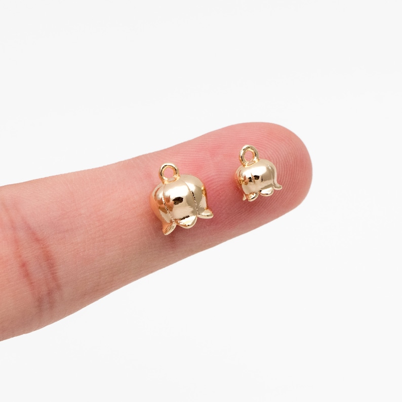May include: Two gold-colored lily of the valley flower charms with a loop for attaching to jewelry or other crafts.
