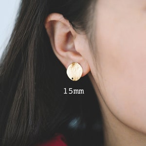 May include: Gold-toned round stud earrings with a textured surface. The earrings are 15mm in diameter.