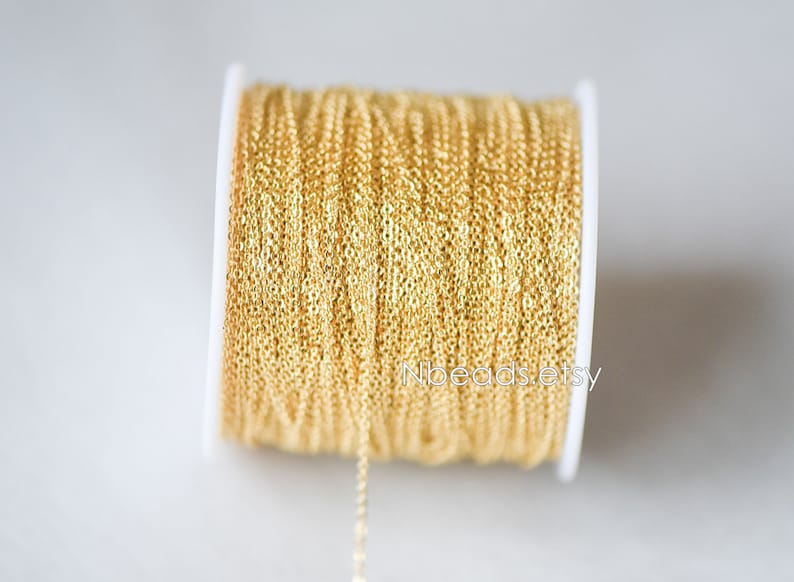 May include: A spool of gold-colored chain, wound around a white plastic spool. The chain is a delicate, fine-link style.
