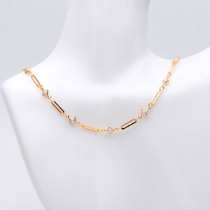 May include: A gold chain necklace with small white pearls set in square-shaped accents.