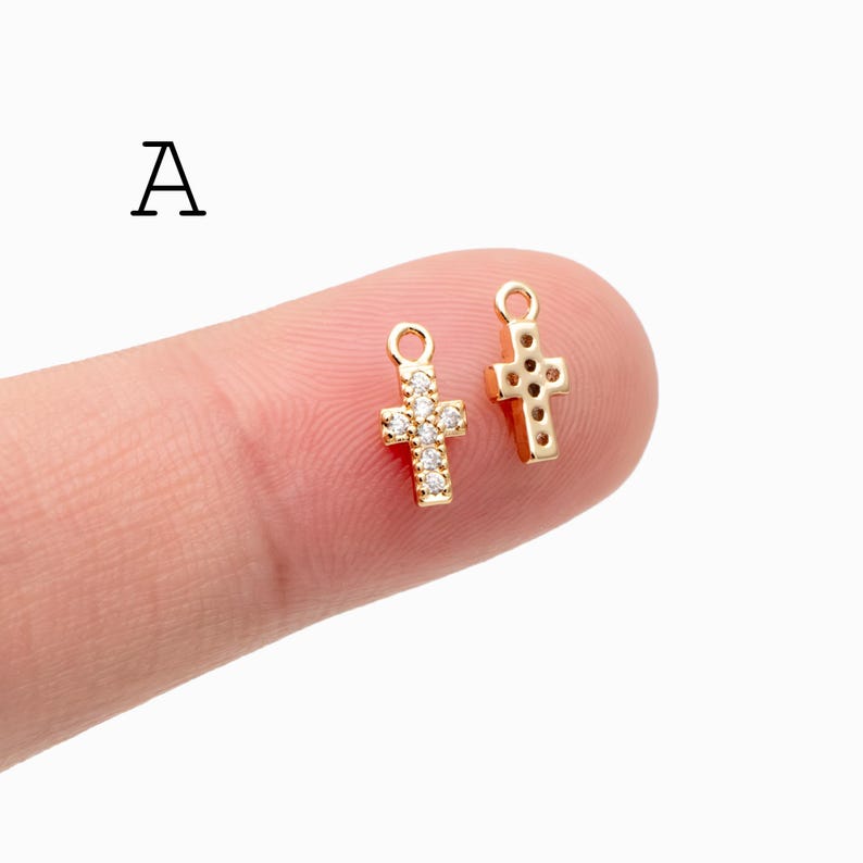 Pu&ograve; includere: Due piccoli ciondoli a forma di croce color oro. Una croce &egrave; incastonata con cristalli trasparenti, mentre l'altra ha un design strutturato. Entrambi hanno un piccolo anello nella parte superiore per il fissaggio. La lettera "A" &egrave; nell'angolo in alto a sinistra.