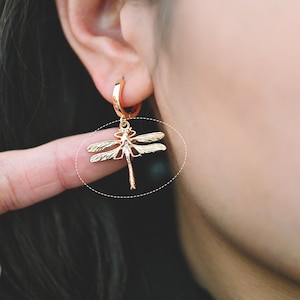 Op de afbeelding: Gouden creolen met een libel-hanger.