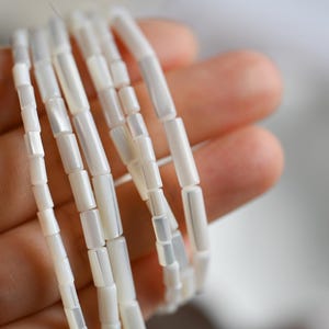 Op de afbeelding: Een witte keramische mok met een zwart handvat en de tekst "But First, Coffee" in een vetgedrukte, zwarte letter. De mok staat tegen een vage achtergrond, wat een gezellige setting suggereert.