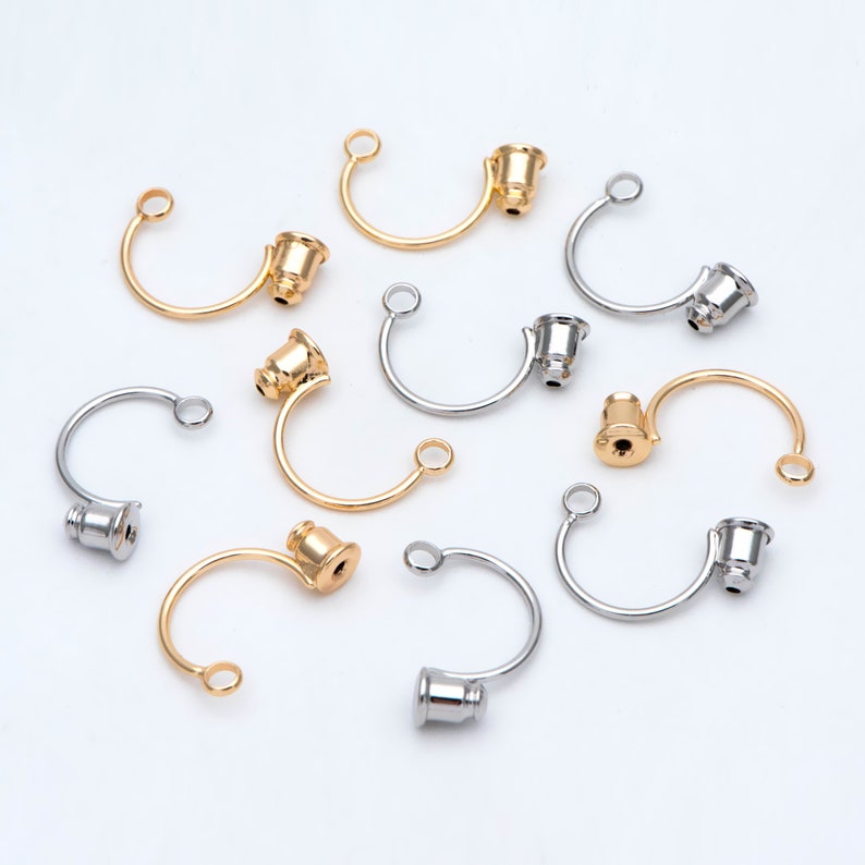 May include: A collection of gold and silver metal jewelry findings with a curved shape and a small round cap on one end. The findings are ideal for making necklaces, bracelets, and earrings.