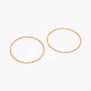 May include: Two gold-toned, thin, textured, circular rings.