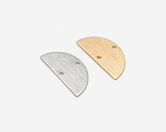 Op de afbeelding: Twee halfronde metalen bedels, een zilveren en een gouden, met elk twee gaten. De bedels hebben een geborstelde afwerking.